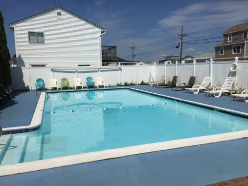 a large swimming pool with chairs and a fence at Regal Inn Hampton Beach in Hampton