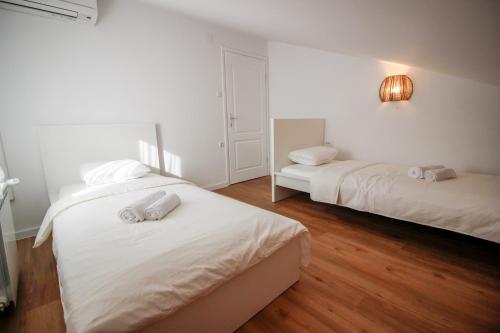 two beds in a room with white walls and wood floors at Apartment Castelmuschio in Omišalj