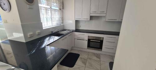 a kitchen with white cabinets and a black counter top at El Sandi 12 in Forster
