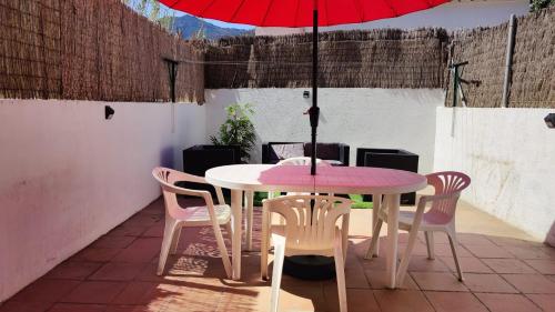 Port de la Selva apartament في بورت دي لا سيلفا: طاولة وكراسي مع مظلة حمراء على الفناء