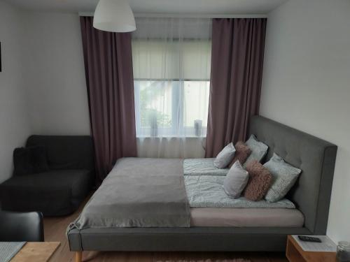 a bedroom with a bed and a chair and a window at Apartament Świerkowa in Lidzbark