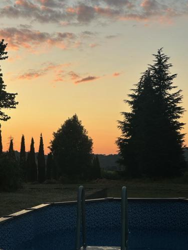 a swimming pool with a sunset in the background at PIAN DEL LECCIONE in Manciano