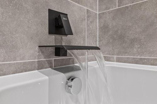 a bath tub with a faucet and a sink at Riverside Rest 1 - 2 Bedroom Apartment & Free Parking Onsite in Stirling