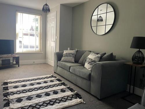 a living room with a couch and a mirror at Oak House by ShortStays4U A Modern 3Bedroom Townhouse with free parking in town! in King's Lynn