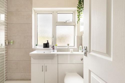 a white bathroom with a sink and a window at Spacious light flat in fantastic location! in Eton