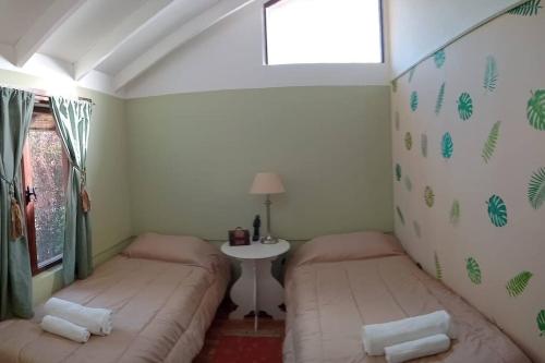 two beds in a room with a table and a window at Depto Acogedor cómodo y súper luminoso en km 7,500 in San Carlos de Bariloche