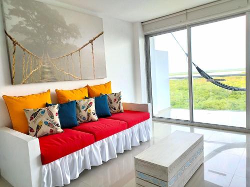 un sofá rojo con almohadas coloridas en la sala de estar. en Morros Epic, en Cartagena de Indias