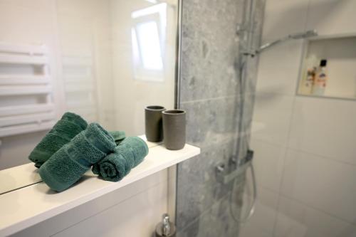 a bathroom with green towels on a shelf and a shower at House La Vista Hvar in Hvar