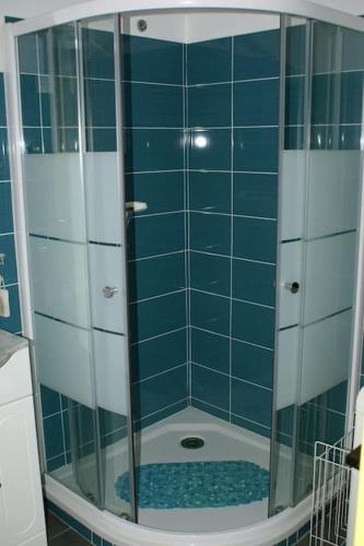 La salle de bains est pourvue d'une douche et de carrelage bleu. dans l'établissement Appartement 1903 Tennis Village, au Cap d'Agde