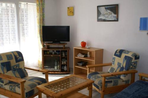 - un salon avec deux chaises et une télévision à écran plat dans l'établissement Appartement 1903 Tennis Village, au Cap d'Agde