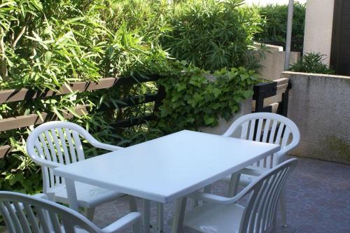 une table blanche et deux chaises avec des plantes dans l'établissement Villa 21, port Venus village au village naturiste, au Cap d'Agde