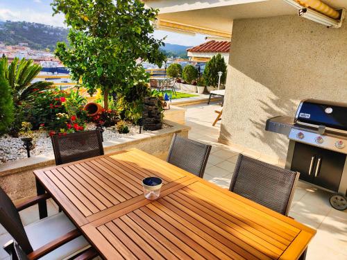 a wooden table and chairs on a patio with a grill at Apartment Luna Tossa De Mar 5mins walking to the beach with sea and castle view big terrace in Tossa de Mar