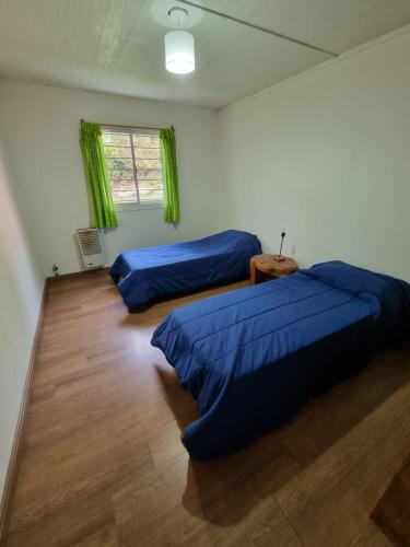 um quarto com 2 camas azuis e uma janela em Villa Amalia em San Carlos de Bariloche