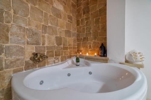 una vasca bianca in un bagno con parete in pietra di Dimora Dante a Ceglie Messapica