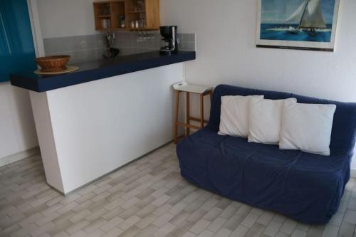 un canapé bleu assis dans une pièce avec un comptoir dans l'établissement Appartement 550, Port Nature 5, village naturiste, au Cap d'Agde
