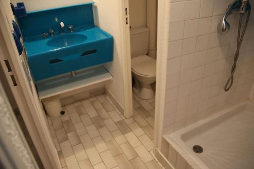 une salle de bain avec un lavabo bleu et des toilettes dans l'établissement Appartement 550, Port Nature 5, village naturiste, au Cap d'Agde