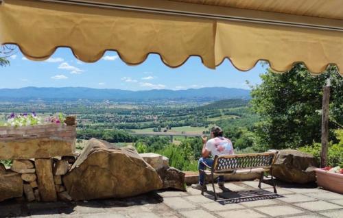 a man sitting on a bench looking out at the mountains at Al Podere del Nonno Romolo in Sansepolcro