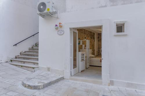 a white house with a door and a staircase at Dimora Dante in Ceglie Messapica