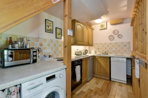 a kitchen with wooden cabinets and a stove top oven at Duddings Country Cottages in Minehead