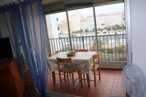une table et des chaises assises sur un balcon avec une fenêtre dans l'établissement Cap d'Agde, la Croisette Appartement 4 personnes, au Cap d'Agde