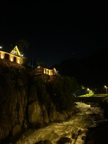 a building on a cliff next to a river at night at Çukur Vadi Evleri in Ardeşen