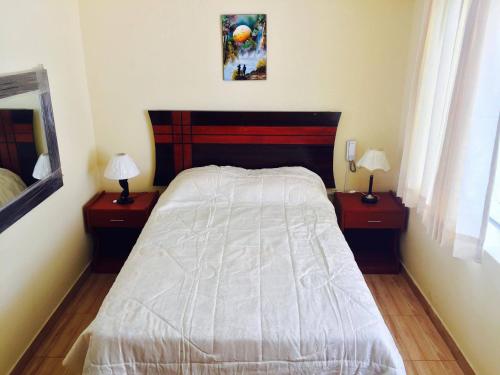 ein Schlafzimmer mit einem Bett und zwei Nachttischen mit Lampen in der Unterkunft HOTEL CASTILLO MAGICO (EX CHAVIN SEÑORIAL? in Barranca
