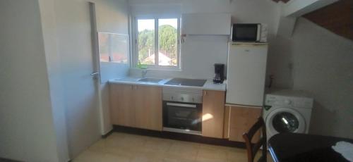 a kitchen with a stove and a sink and a window at Ginjals_67 in Almargem do Bispo