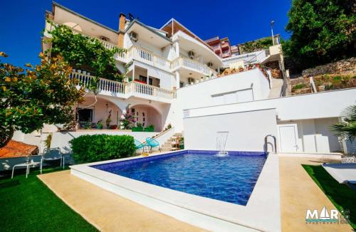 a villa with a swimming pool in front of a house at Apartments Mar in Ulcinj