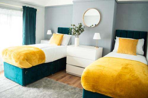 2 camas en un dormitorio con amarillo y azul en Luxury Cityscape London - Free Parking!, en Ealing