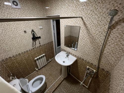 a bathroom with a sink and a toilet and a mirror at Dilnura Guest House in Bukhara