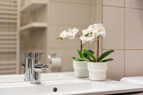 een wastafel in de badkamer met een vaas met bloemen erop bij Ráday Boutique Apartment in Boedapest