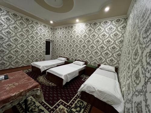 two beds in a room with wallpaper at Dilnura Guest House in Bukhara
