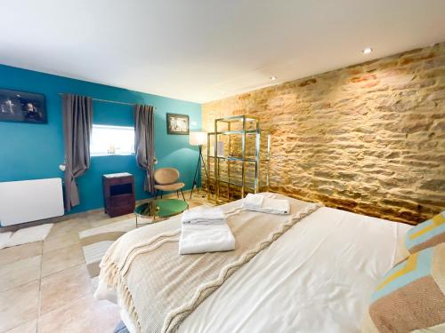 a bedroom with a large bed and a stone wall at La Ferme du Bois - Piscine et Spa in Plottes