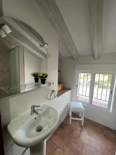 a white bathroom with a sink and a mirror at Casa rural Las Casillas in Málaga