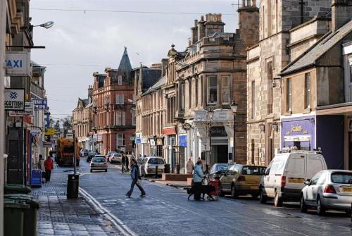 people walking down a city street with cars and buildings at Nairn View Guest House in Nairn