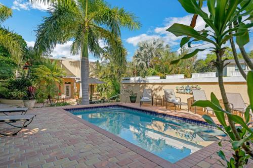 a swimming pool with chairs and palm trees at Banyan House Vacation Rentals in Venice