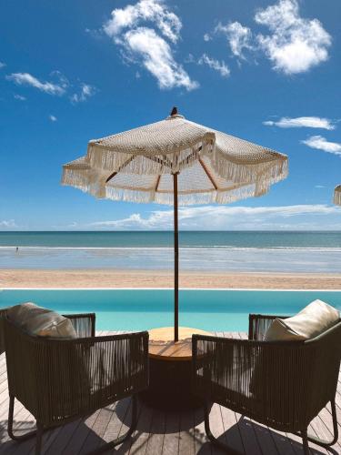 a table and chairs under an umbrella on the beach at Villa Mango in Icaraí