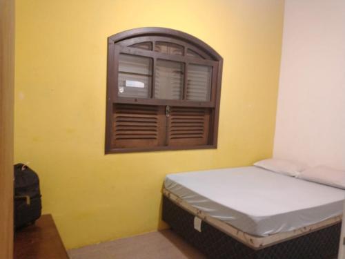 um pequeno quarto com uma cama e uma janela em Ilhabela 150m da praia em Ilhabela