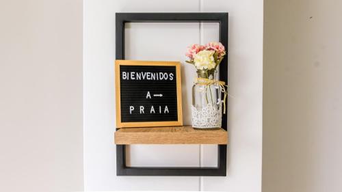 a shelf with a chalkboard and a vase of flowers at Praia Apartaestudios Sabaneta in Sabaneta