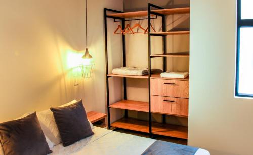 a bedroom with a bed and a closet with shelves at Praia Apartaestudios Sabaneta in Sabaneta