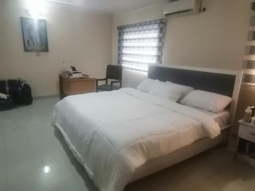 Schlafzimmer mit einem großen weißen Bett und einem Schreibtisch in der Unterkunft Luxury Homes in Port Harcourt