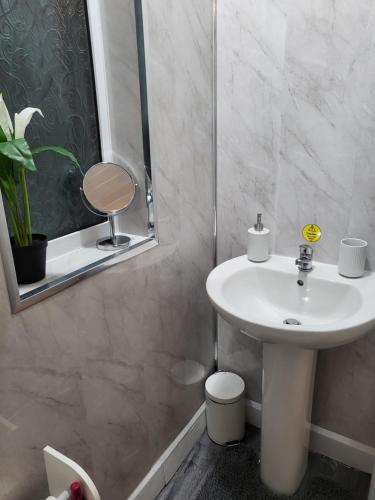 uma casa de banho com um lavatório branco e um espelho. em Coventry Cosy Home - Perfect location for Contractors, Families, Relocators, close Walsgrave Hospital and Motorways em Wyken