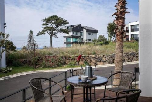 a table and chairs on a balcony with a house at Aewol Bada Poomeun Property in Jeju