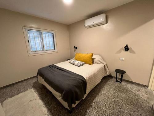 een slaapkamer met een bed met gele kussens en een raam bij CASA EN YERBA BUENA in Yerba Buena