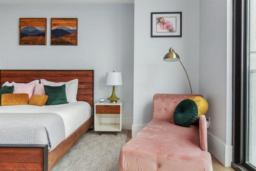 um quarto com uma cama e uma cadeira rosa em 'Mountain Gem' A Luxury Downtown Condo with Mountain and City Views at Arras Vacation Rentals em Asheville