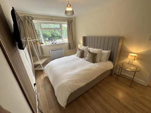 a bedroom with a bed with white sheets and a window at Charming 2-Bed Apartment in Danbury essex in Chelmsford