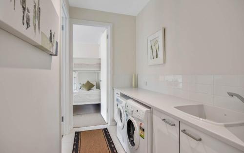 a white kitchen with a washing machine and a sink at No 7 Summer Salts in Hayborough