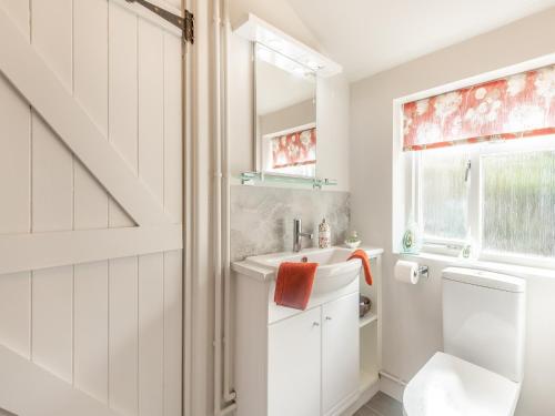 baño con lavabo y aseo y ventana en Hazel Cottage, en Tolpuddle