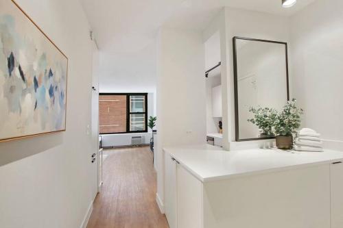 a white bathroom with a mirror and a sink at Serene & Completely Furnished Studio Apartment- Chestnut 14F in Chicago