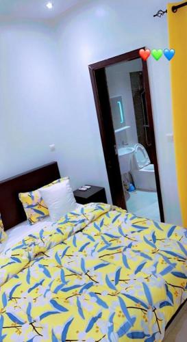 a bedroom with a bed with a yellow and blue comforter at Sweet home in Dakar